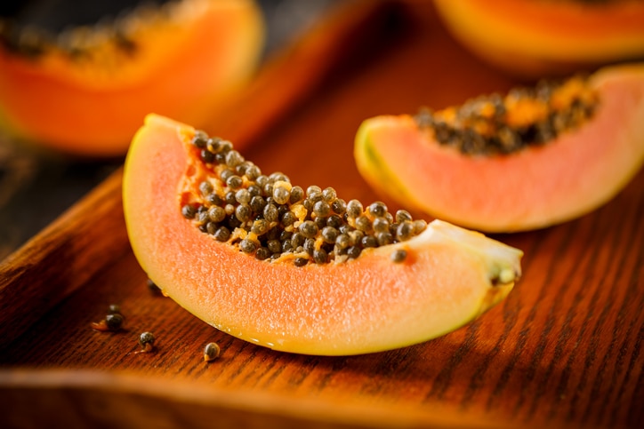 Halved and whole papaya fruits on the background