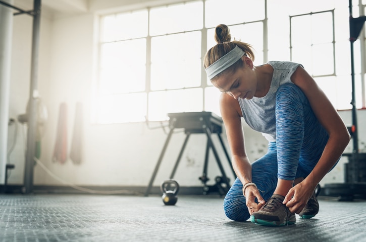 Shot of a young attractive woman tying her shoelaces in a gym