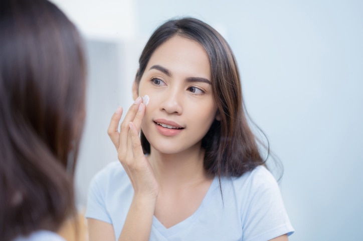 Shot of a beautiful young woman applying moisturizer to her skin in the bathroom at home