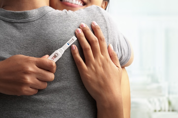 Joyful couple with positive pregnancy shown in the test device