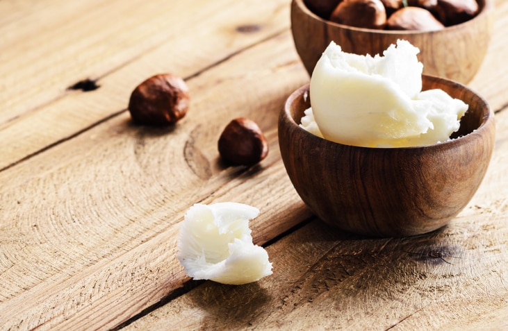 Shea butter and nuts on a wooden board, copy space.