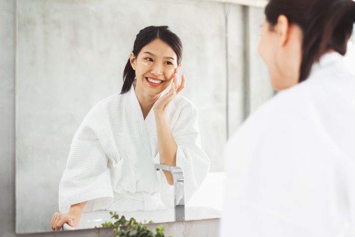 Asian woman cleaning face front of mirror, skin care and cosmetic removal concept