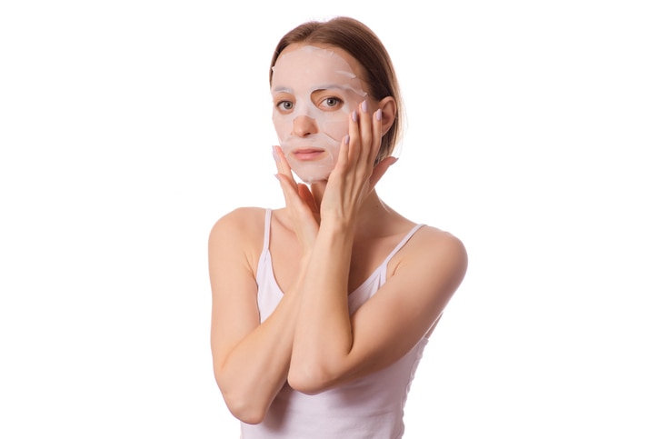 Beautiful young woman a tissue mask on her face beauty cosmetics on a white background isolation