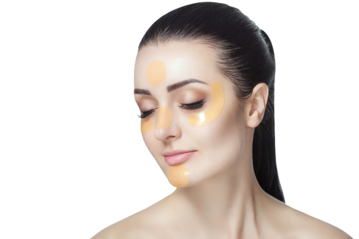 Collagen gold patches on the skin of the eyelid, forehead and chin on the face of a beautiful woman.