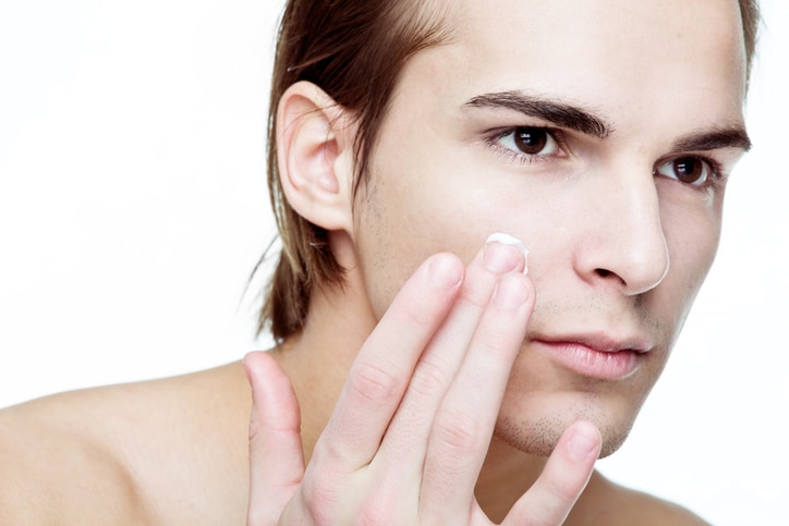 Man applying cosmetic cream on face