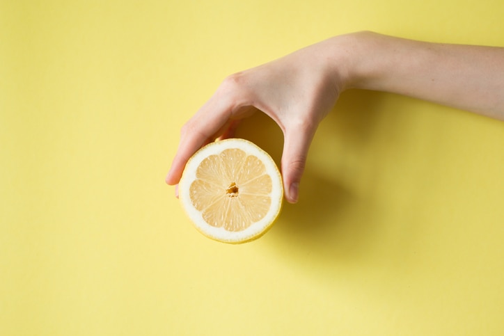 Lemon in woman's hand on a yellow background