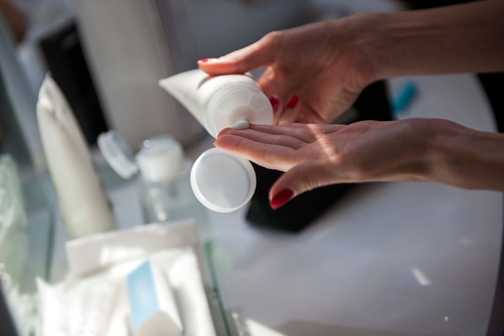 Woman's hands using cosmetic cream