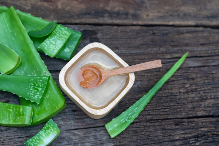 Fresh aloe vera stem and gel on wooden table, skin therapy concept, copy space