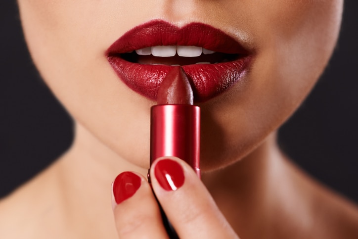 Closeup image of a woman applying lipstick