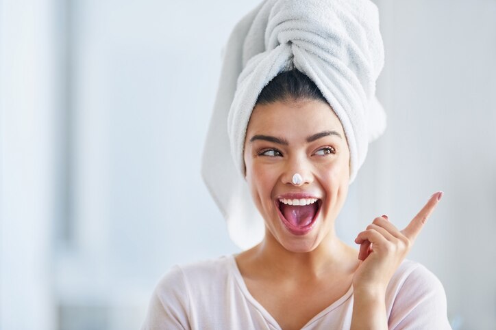 Shot of a beautiful young woman applying moisturizer to her skin in the bathroom at home