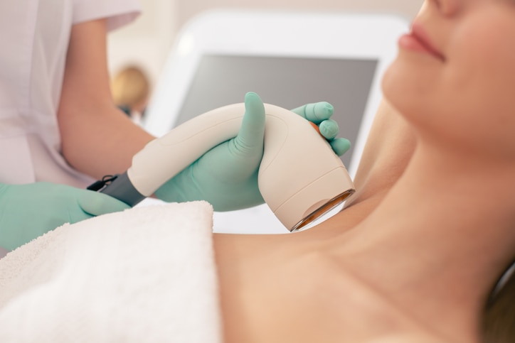 Selective focus of special device with a vacuum suction and hand in glove holding it near the neck of woman