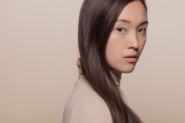 Portrait of woman with straight brown hair. Asian woman with a long hair looking at camera.