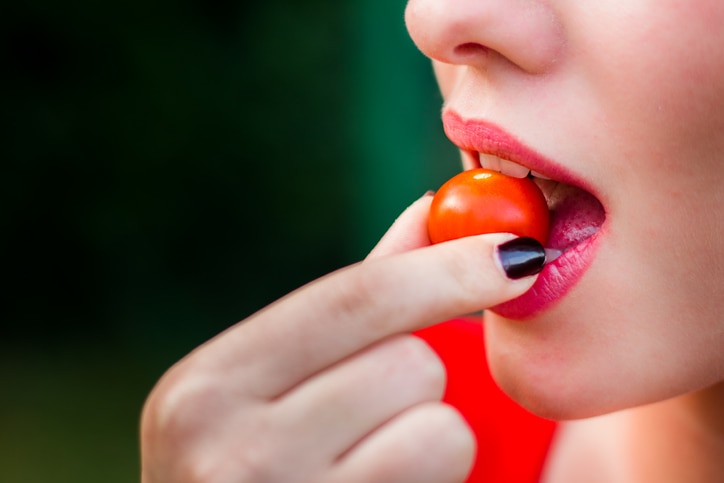 Young woman eating a cherry tomatoes