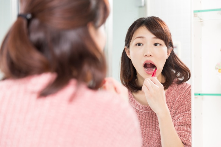 young attractive asian woman with healthy teeth holding a tooth brush