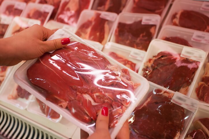 Image of packaged meat with woman hand in the supermarket