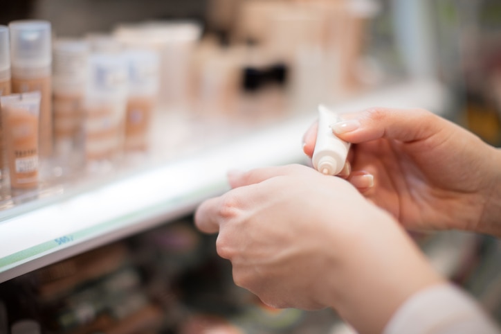 Unrecognizable person trying perfect concealer color in cosmetics store