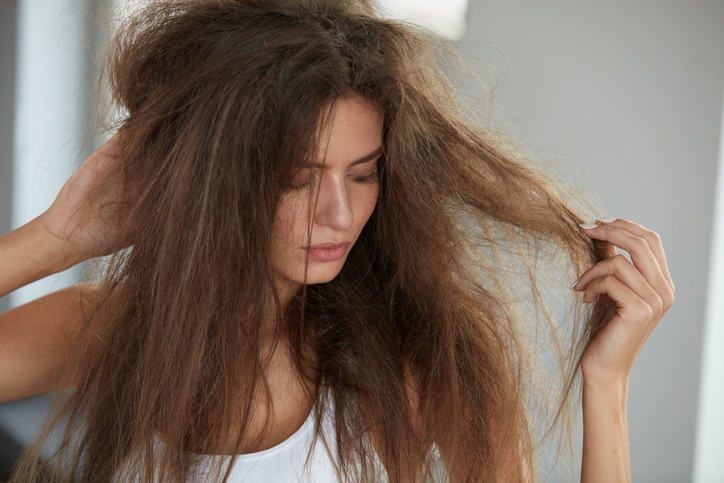 Damaged Hair. Beautiful Sad Young Woman With Long Disheveled Hair. Closeup Portrait Of Female Model Holding Messy Unbrushed Dry Hair In Hands. Hair Damage, Health And Beauty Concept. High Resolution