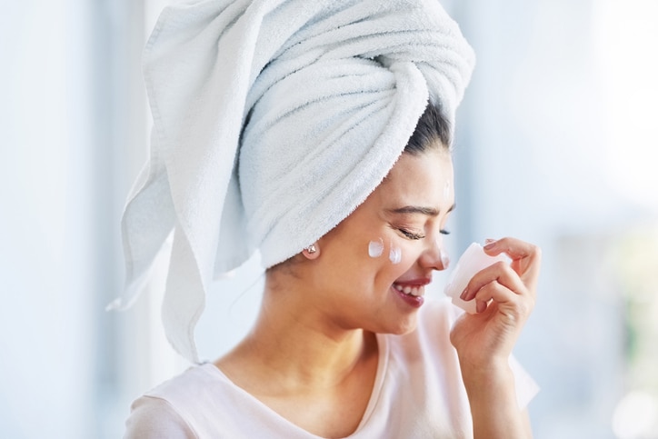 Shot of a beautiful young woman applying moisturizer to her skin in the bathroom at home