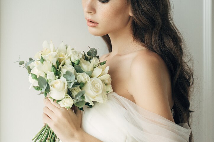 Studio shot of young beautiful bride on light background. Professional make-up and hairstyle.