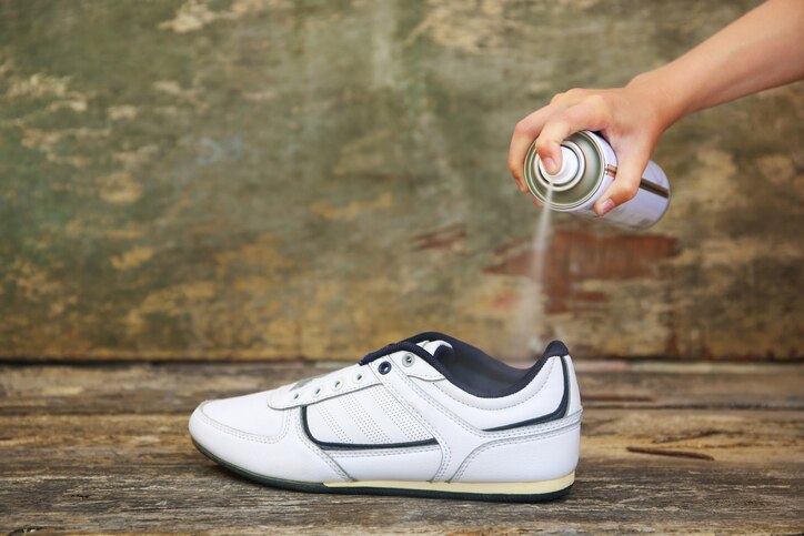 Female hand holding a spray deodorant for shoes.